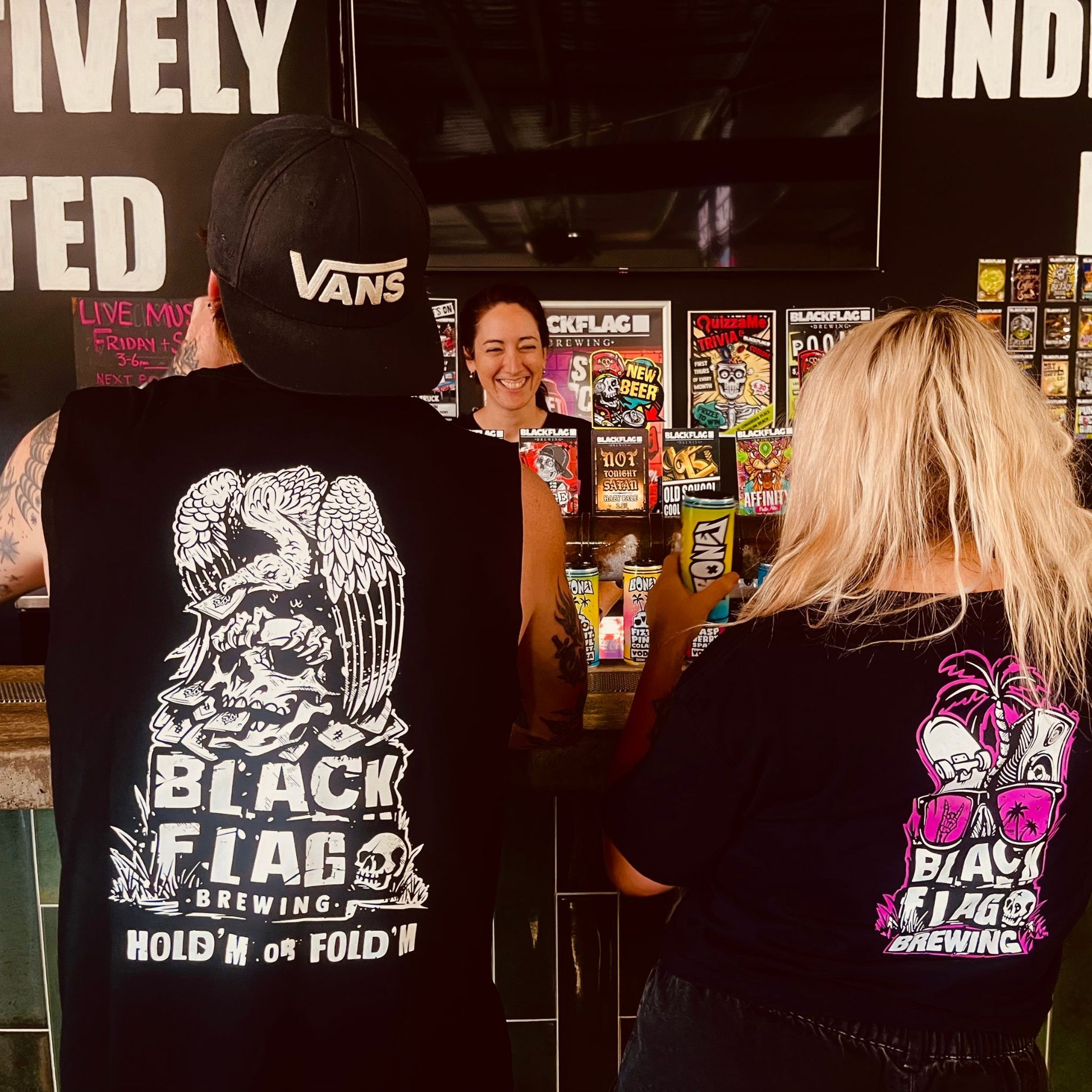 Man wearing a black Blackflag tank top with hand drawn Hold ‘Em Or Fold ‘Em illustration on back.